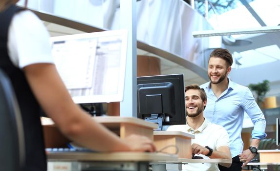 Group of young confident business people analyzing data using computer while spending time in the office.