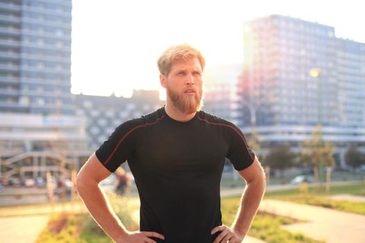 Handsome young man after run resting after jog at the park at sunset or sunrise