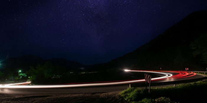 vegicle light trails in night on busy countryroad curve  long exposure