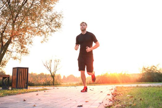 Sporty young man running outdoors to stay healthy, at sunset or sunrise. Runner