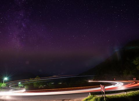 vegicle light trails in night on busy countryroad curve  long exposure