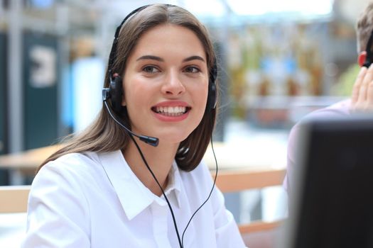 Female customer support operator with headset and smiling.