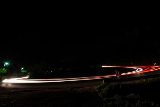 vegicle light trails in night on busy countryroad curve  long exposure