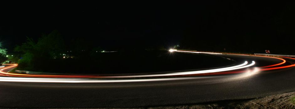 vegicle light trails in night on busy countryroad curve  long exposure