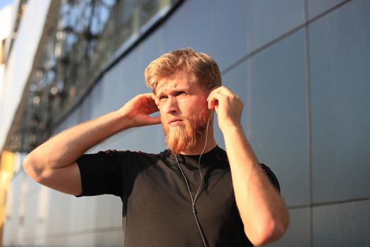 Portrait of a young sports man running with headphones.