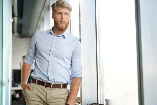 Portrait of a happy young casual businessman at office, smiling.