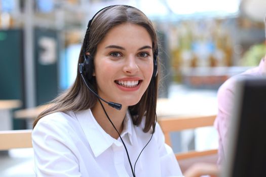 Female customer support operator with headset and smiling.