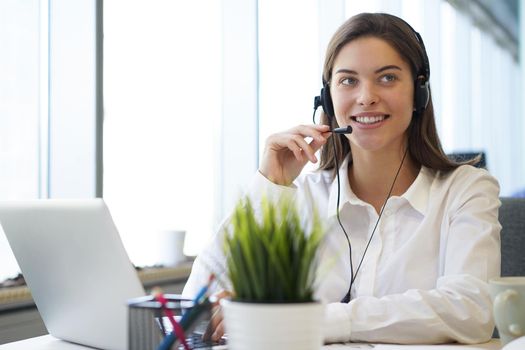 Female customer support operator with headset and smiling.