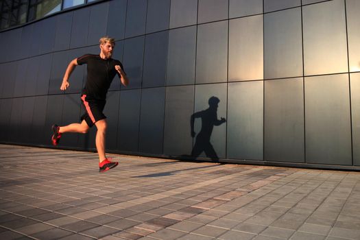 Sporty young man running outdoors to stay healthy, at sunset or sunrise. Runner