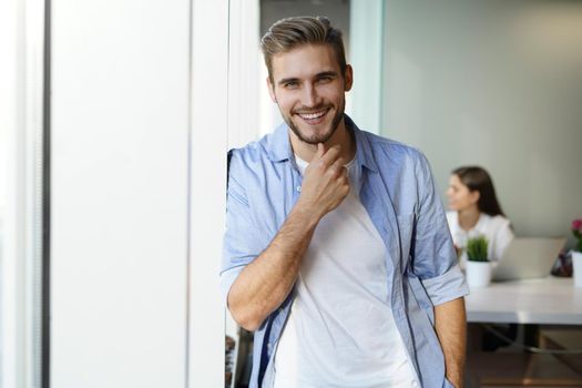 Portrait of a happy young casual businessman at office, smiling.