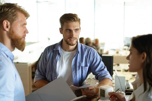 Young colleagues in smart casual wear working while spending time in the office.