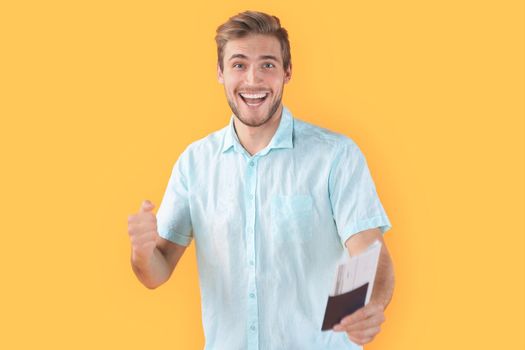 Young man isolated over yellow background holding passport pointing