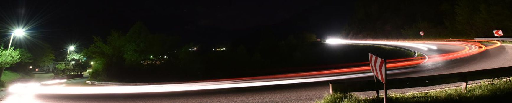 vegicle light trails in night on busy countryroad curve  long exposure