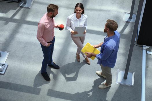 Top view of young modern people in smart casual wear discussing business while standing in creative office