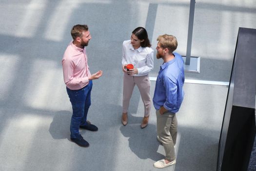 Top view of young modern people in smart casual wear discussing business while standing in creative office