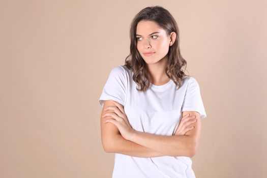 Young woman in casual clothing wondering and screaming isolated over beige background