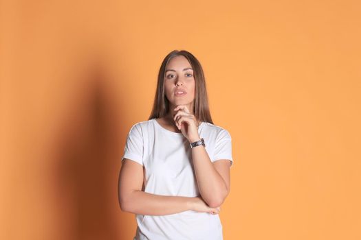 Young woman in basic clothing smiling and pointing finger at copyspace isolated on yellow background.