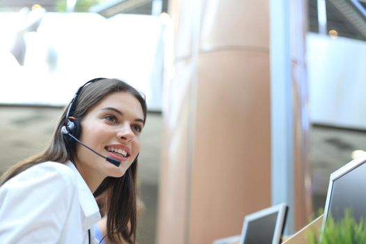 Female customer support operator with headset and smiling.