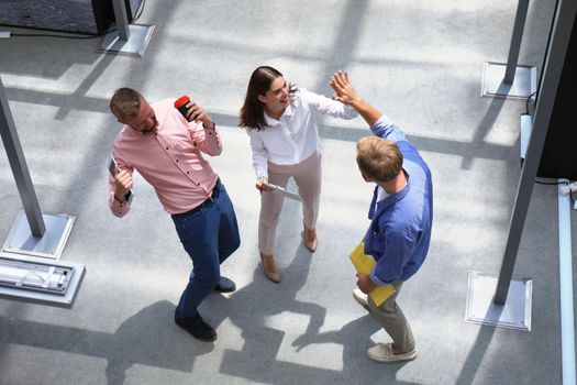 Top view of young modern people in smart casual wear discussing business while standing in creative office