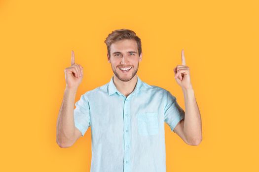 Young happy man posing isolated over yellow background pointing