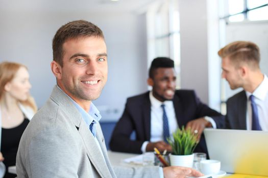 Businessman with colleagues in the background in office.