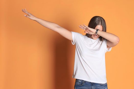 Young woman in basic clothing throws dab isolated on yellow background.