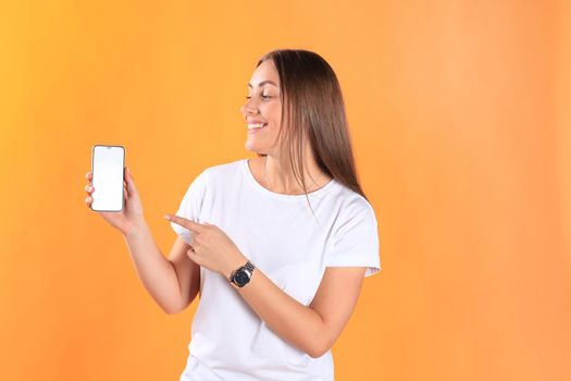 Young woman dressed in basic clothing isolated on yellow background, using mobile phone.