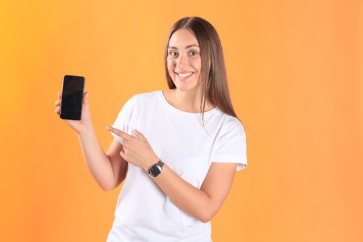 Young woman dressed in basic clothing isolated on yellow background, using mobile phone.