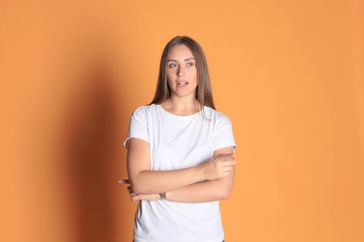 Young woman in basic clothing smiling and pointing finger at copyspace isolated on yellow background.