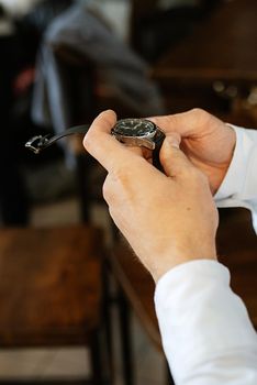 the man in the brown suit looks at his watch, hand clock