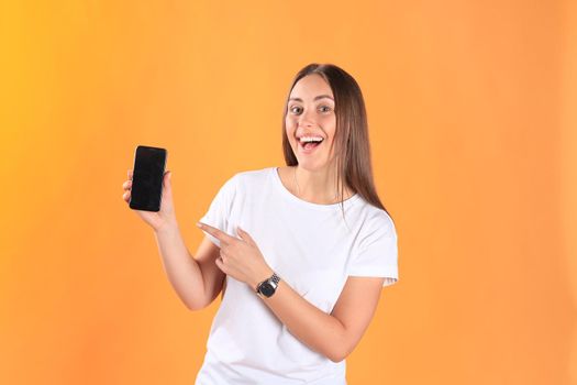 Young woman dressed in basic clothing isolated on yellow background, using mobile phone.