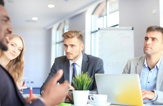 Business people in discussing something while sitting together at the table.