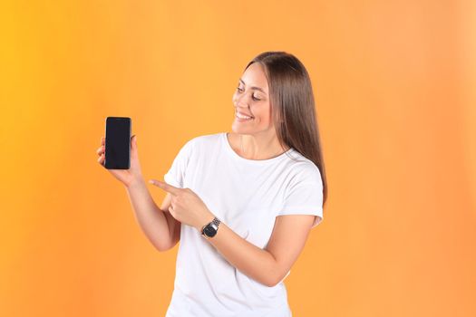 Young woman dressed in basic clothing isolated on yellow background, using mobile phone.