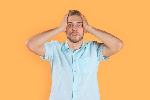 Shocked young man celebrating success isolated over yellow background