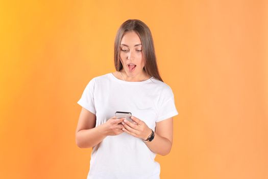 Young woman dressed in basic clothing isolated on yellow background, using mobile phone.