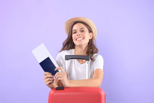 Young tourist girl in summer casual clothes, with sunglasses, red suitcase, passport isolated on purple background