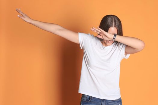 Young woman in basic clothing throws dab isolated on yellow background.