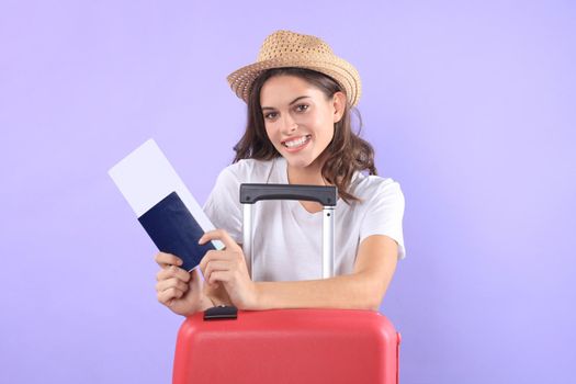 Young tourist girl in summer casual clothes, with sunglasses, red suitcase, passport isolated on purple background