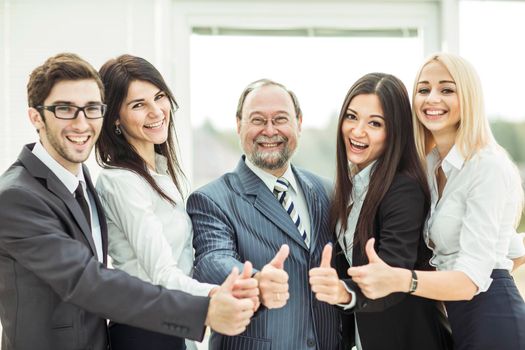 close-up - friendly business team standing nearby and makes a gesture of thumbs up