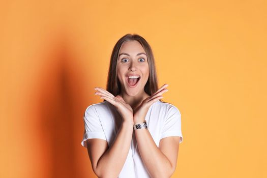 Young woman in casual clothing wondering and screaming isolated over yellow background.