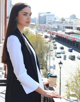 Closeup portrait of relaxing on balcony business woman isolated on background of city buildings.