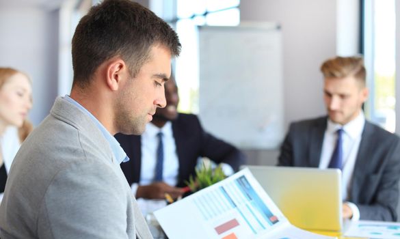 Businessman with colleagues in the background in office.