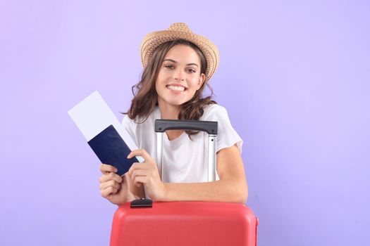 Young tourist girl in summer casual clothes, with sunglasses, red suitcase, passport isolated on purple background