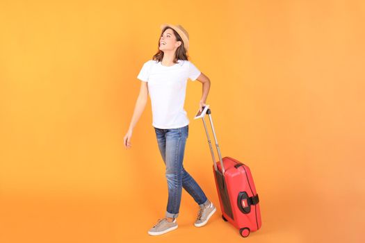 Young tourist girl in summer casual clothes, with red suitcase, passport, tickets isolated on beige background