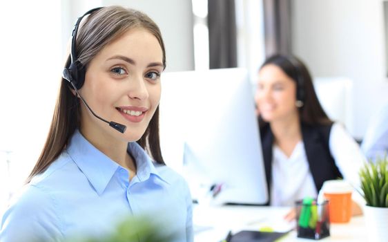 Smiling female call centre operator doing her job with a headset while looking at camera