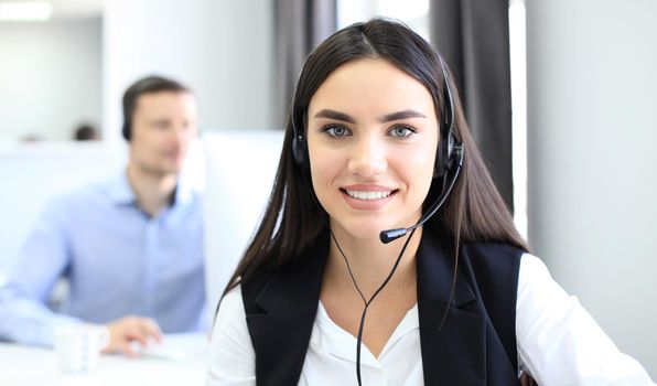 Businesswoman wearing microphone headset using computer in the office - operator, call center.