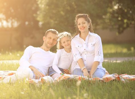 pregnant mother,happy father and daughter on a picnic in the Park on Sunday