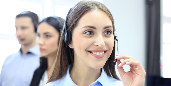 Businesswoman wearing microphone headset using computer in the office - operator, call center.