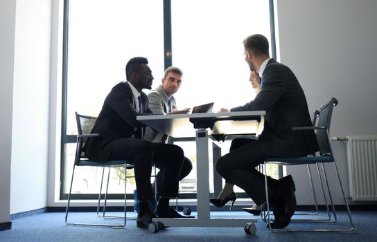 Business people in discussing something while sitting together at the table.