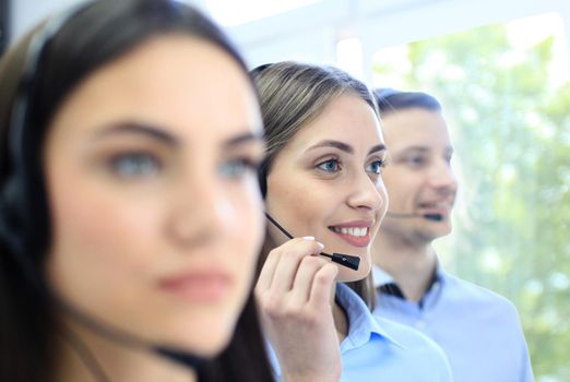 Portrait of call center worker accompanied by her team. Smiling customer support operator at work.